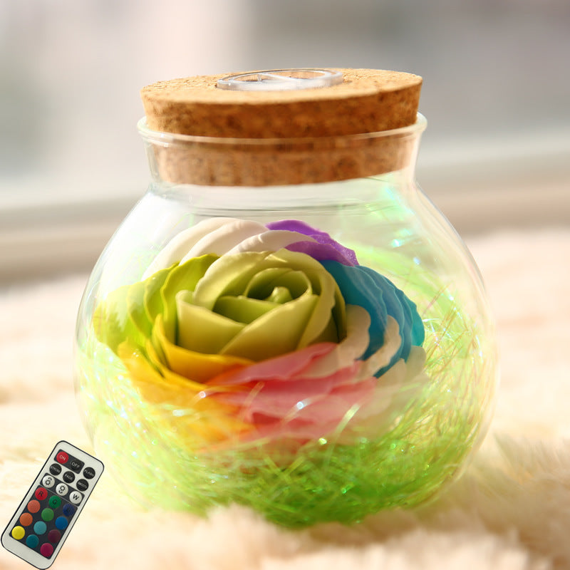 Glass jar with a wooden lid containing colorful LED lights, remote control on the side.