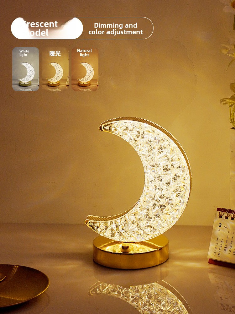 Decorative moon-shaped lamp with dimming and color adjustment features on a reflective surface.