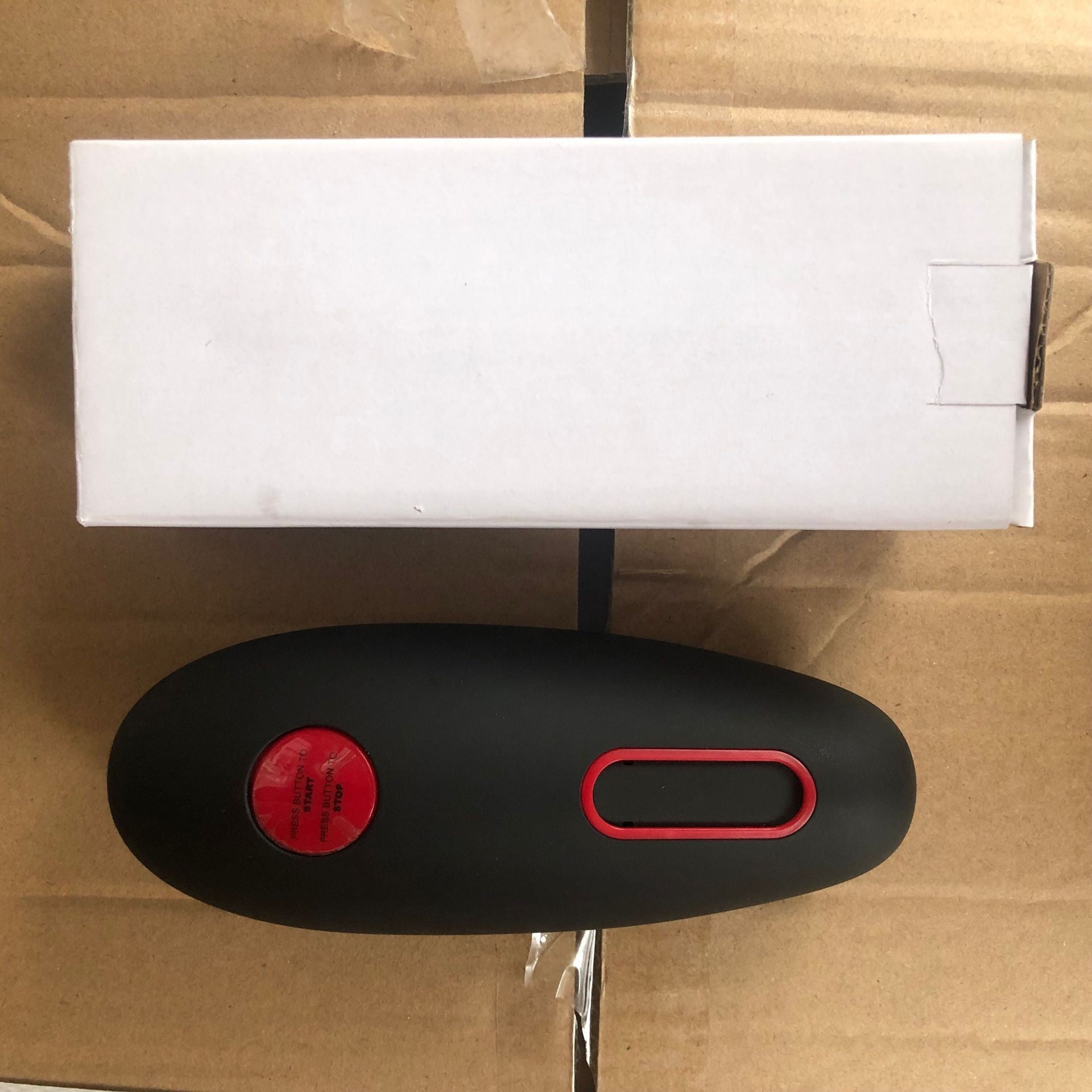 Black and red electronic device on a cardboard surface
