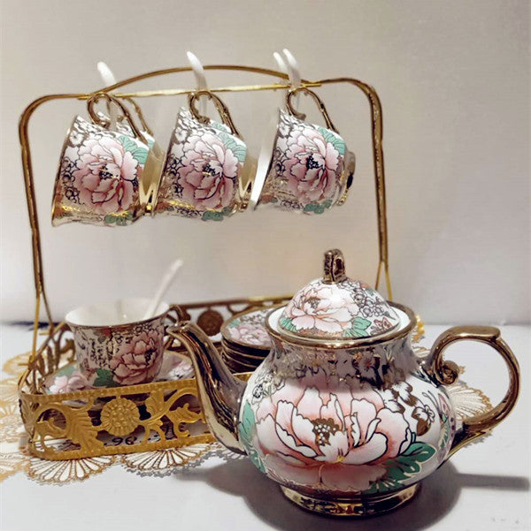 Decorative teapot and cups with floral patterns on a stand.