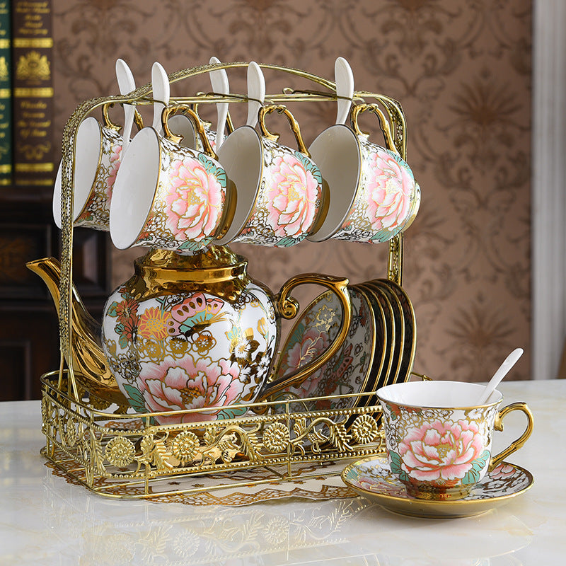 Decorative tea set with floral design on cups and saucers, placed in a decorative stand.
