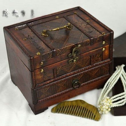 Wooden jewelry box with decorative patterns, accompanied by a comb and pearl necklace on a light background.