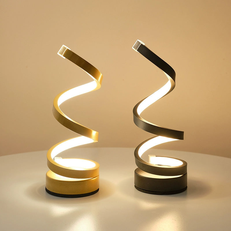 Two spiral-shaped lamps, one gold and one black, on a beige background.