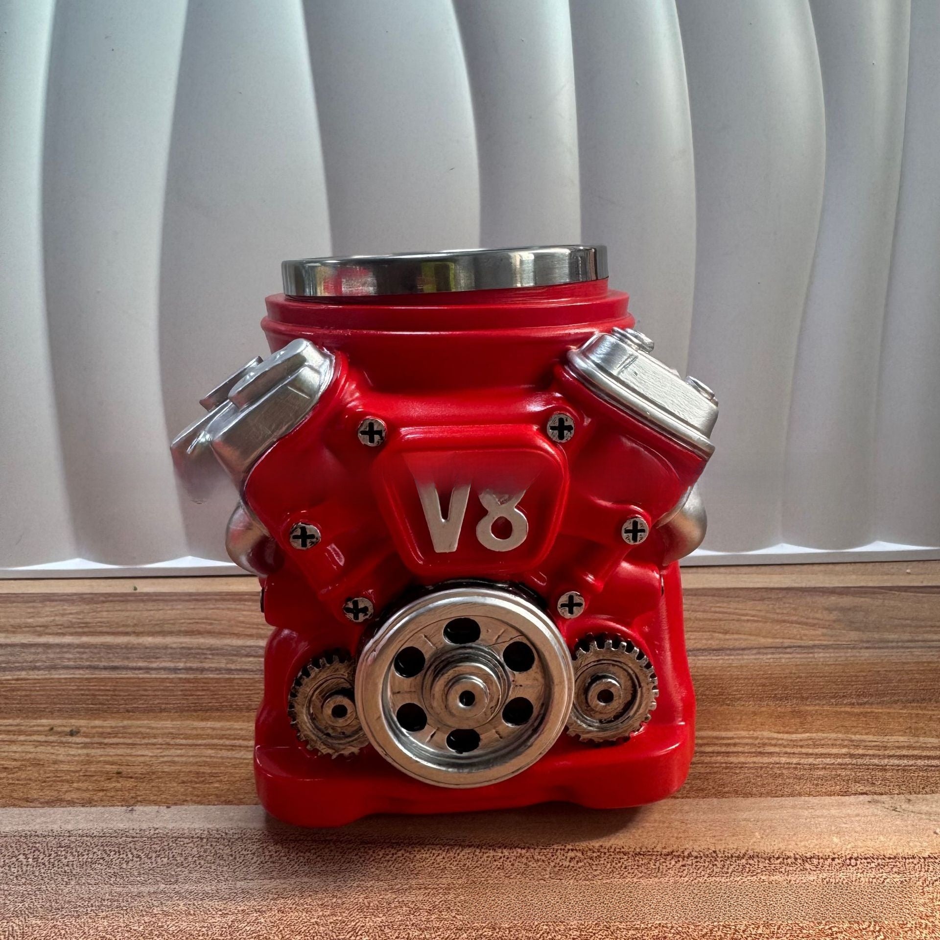 Red V8 engine model on a wooden surface with white curtain background