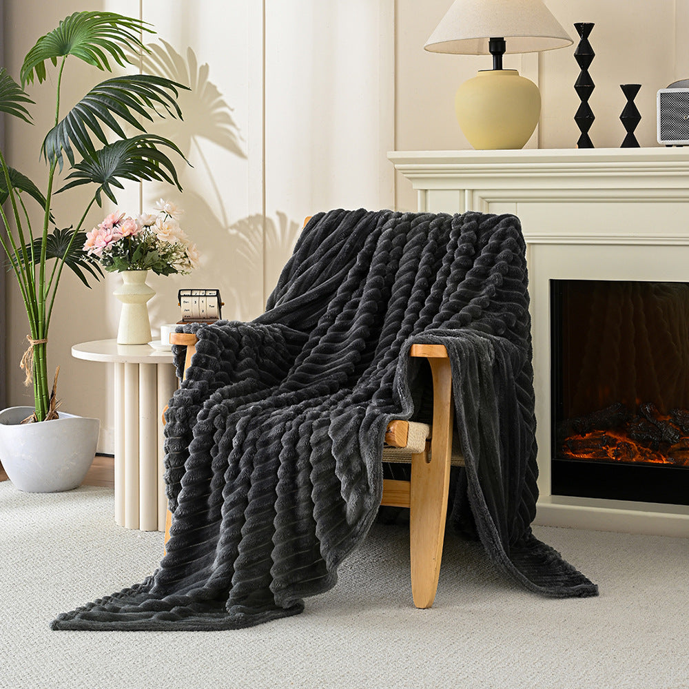 Dark gray textured blanket draped over a wooden chair in a cozy living room with a fireplace.