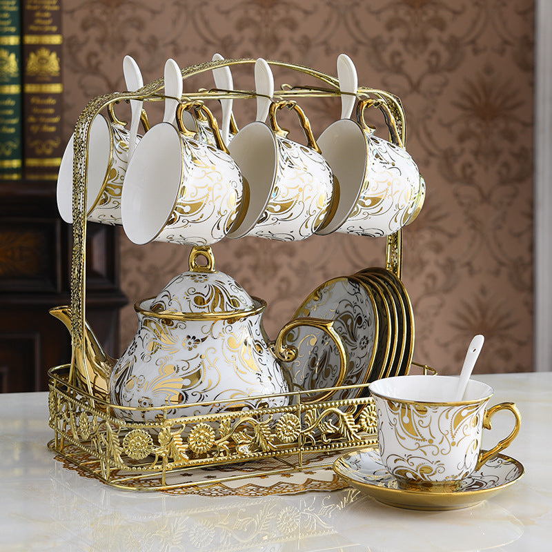 Decorative tea set with gold and white design on a marble surface.