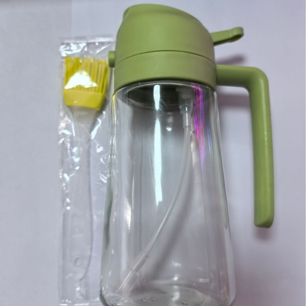 Clear glass bottle with green lid and handle on a white background