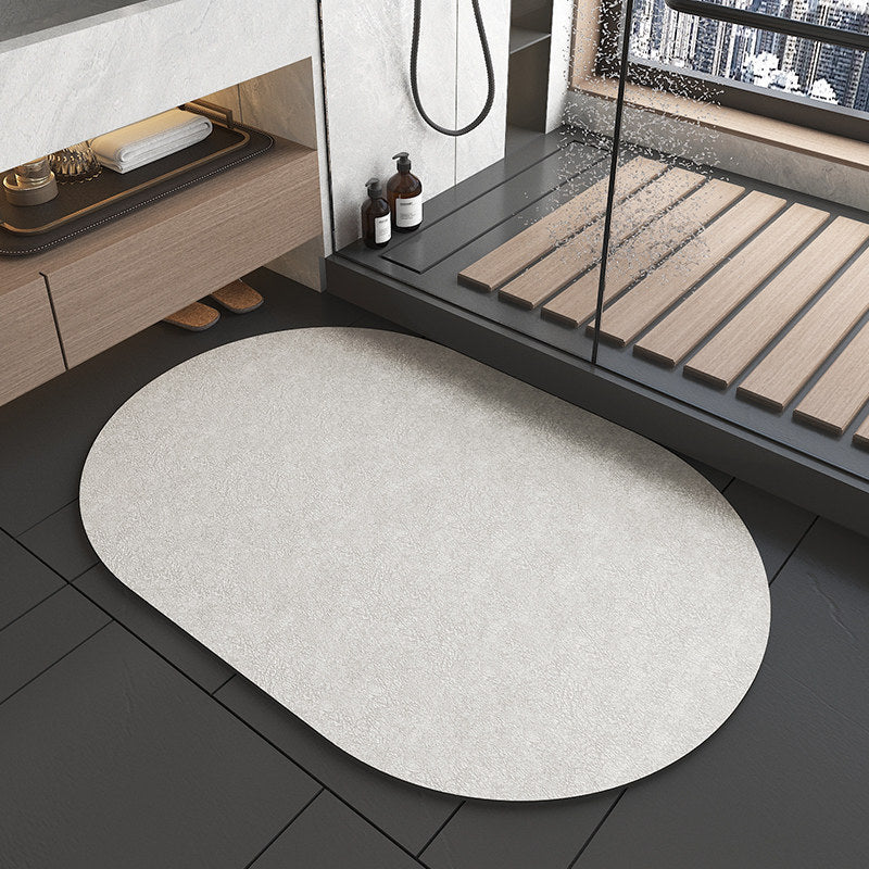Round gray rug on a black tiled floor with a shower area in the background.