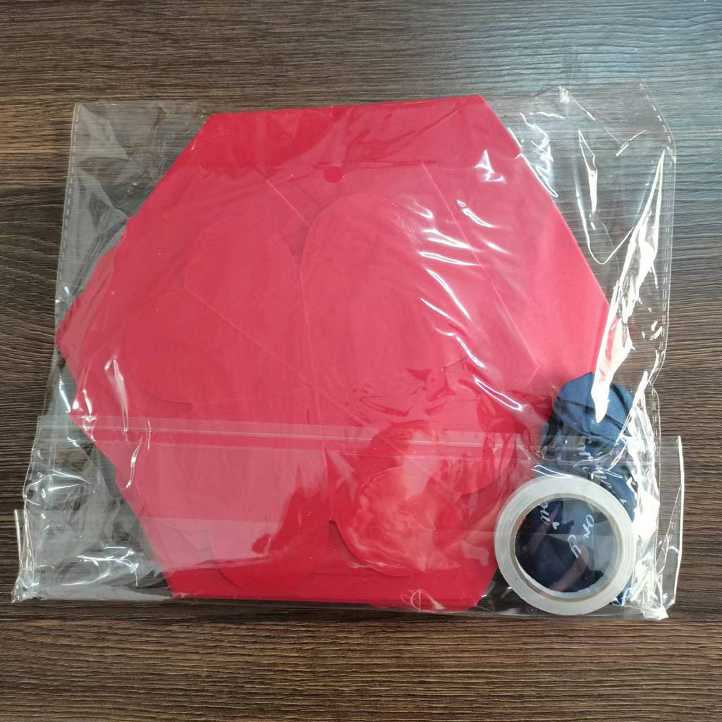 Red silicone mat with blue handle and white tape inside a clear plastic bag on a wooden surface.