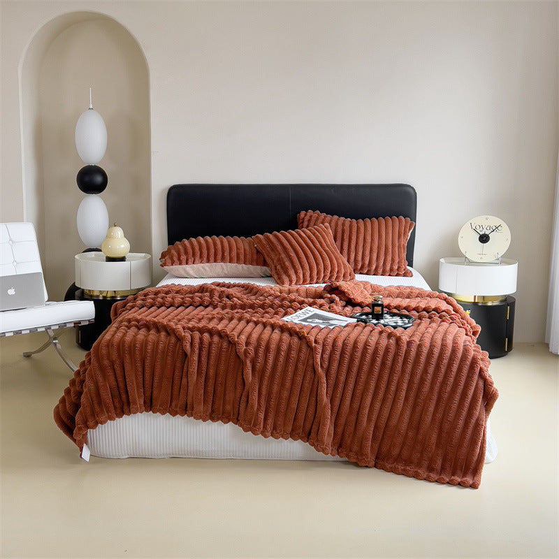 Bedroom with a bed covered in a brown textured blanket and pillows, white walls, and minimal decor.