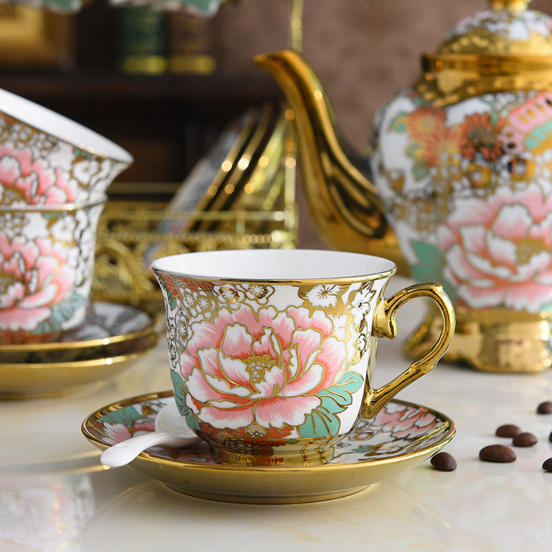 Decorative teacup with floral design on a saucer, surrounded by other tea sets.