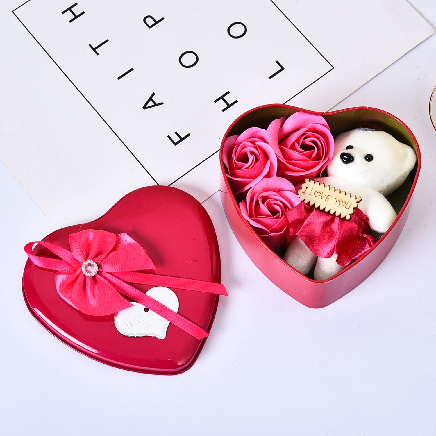 Heart-shaped gift box with pink roses and a small white bear inside, on a light background.
