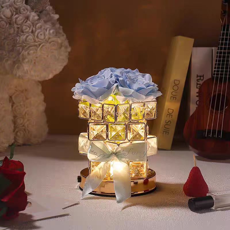 Decorative lamp with flowers and lights on a table with books and a guitar in the background