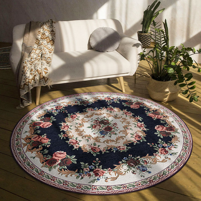 Decorative round rug with floral pattern on a wooden floor in a room with a white sofa and plants.