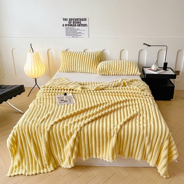 Yellow textured blanket draped over a bed in a bedroom setting.