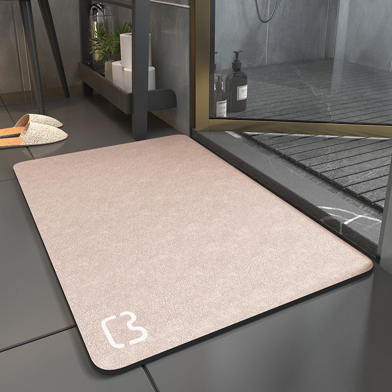 Beige doormat with a brand logo on a tiled floor next to a glass door.