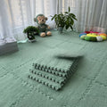 Green interlocking foam mats on a floor with toys and plants in the background.