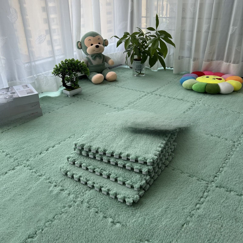 Green interlocking foam mats on a floor with toys and plants in the background.