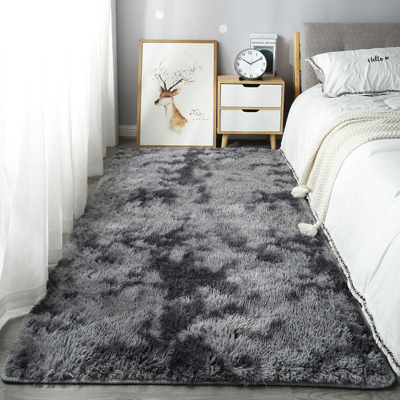 Gray shaggy rug in a bedroom with a bed, nightstand, and wall art.