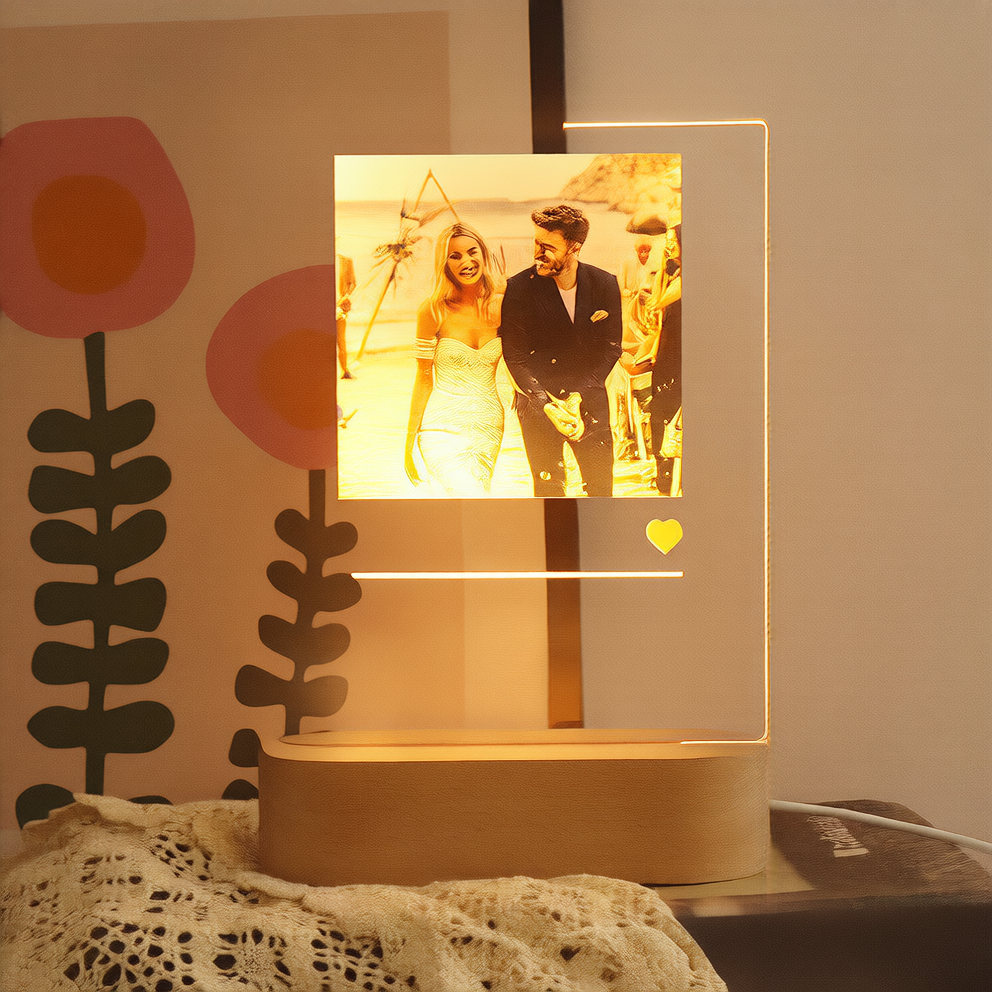 Lamp with a photo of a couple on it, placed on a surface with decorative elements in the background.