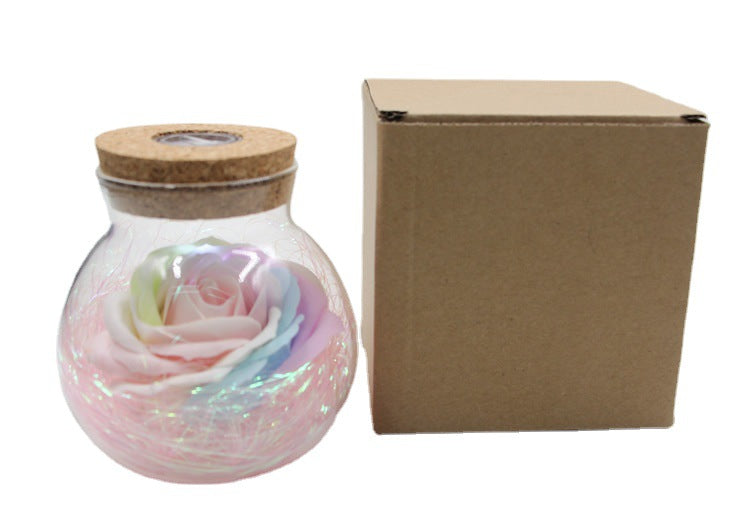 Iridescent rose in a glass jar with a cardboard box on a white background