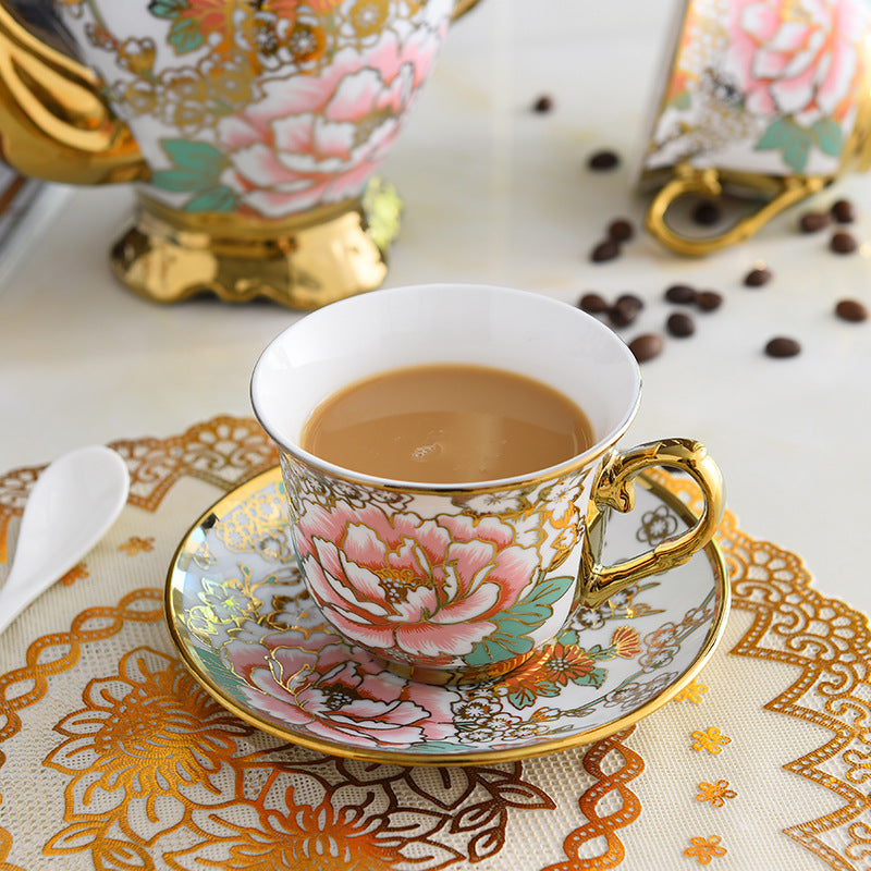 Decorative teacup with floral design on a saucer, filled with tea, on a patterned tablecloth.