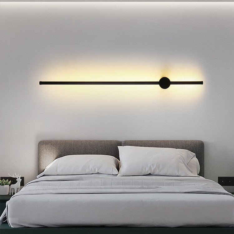 Modern wall-mounted light fixture above a bed in a bedroom setting.
