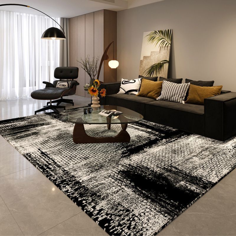 Modern living room with a black and white patterned rug, dark sofa, and decorative elements.