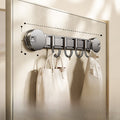 Wall-mounted hook with multiple hooks holding bags on a metallic surface