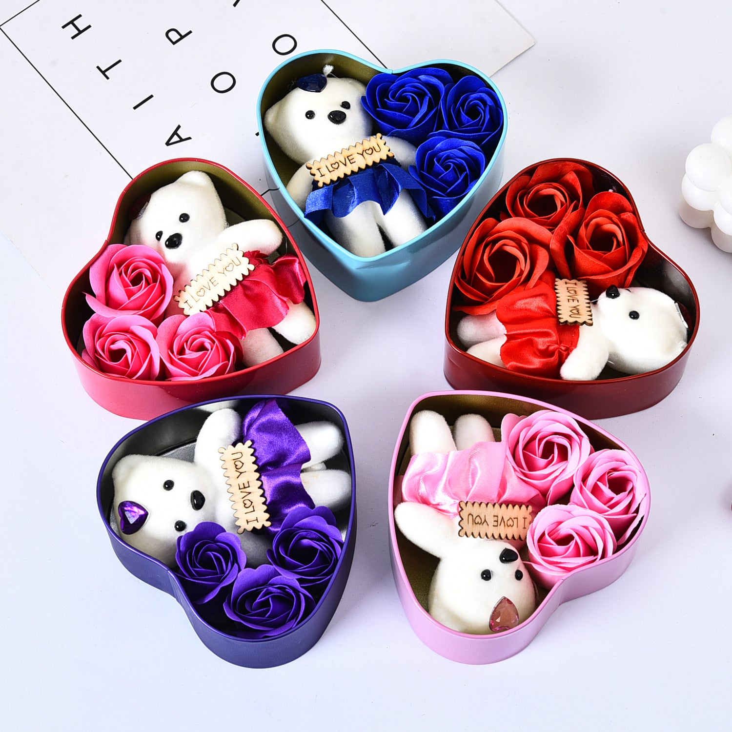 Heart-shaped boxes with teddy bears and flowers on a white background
