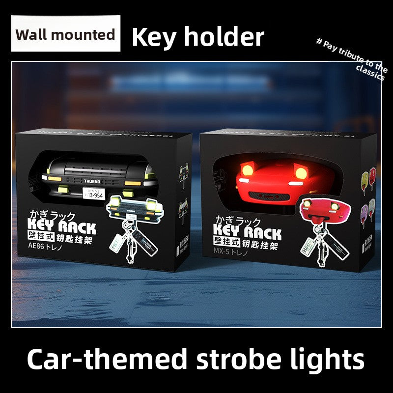 Two key holder packaging boxes with car-themed designs and strobe lights on a dark background.
