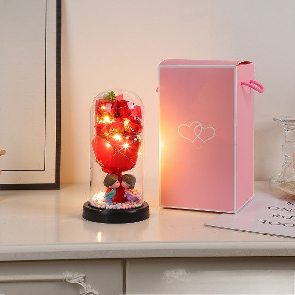 Decorative lamp with red balloon and couple figurines inside a glass dome on a white surface.