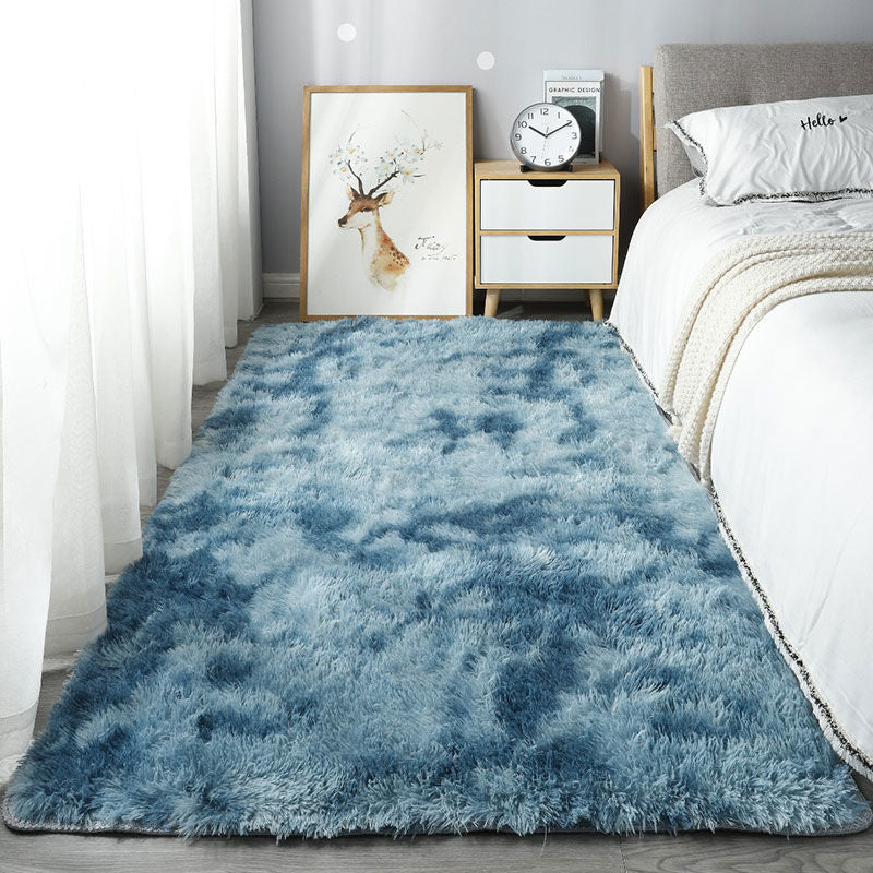 Blue shaggy rug in a bedroom setting with a bed and nightstand.
