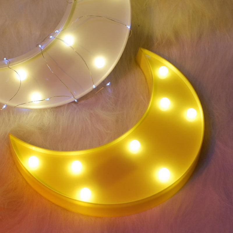 Decorative moon-shaped light with glowing bulbs on a soft surface