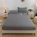 Gray bedspread set on a bed in a bedroom with nightstands and decor.