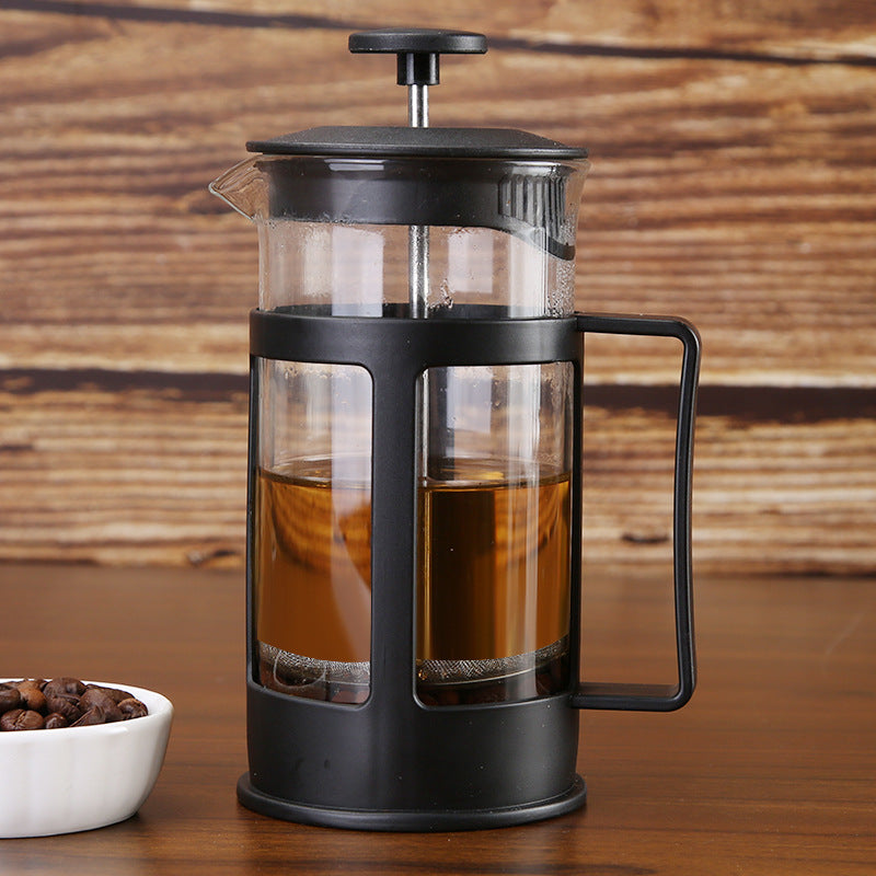 Black French press with coffee on a wooden surface