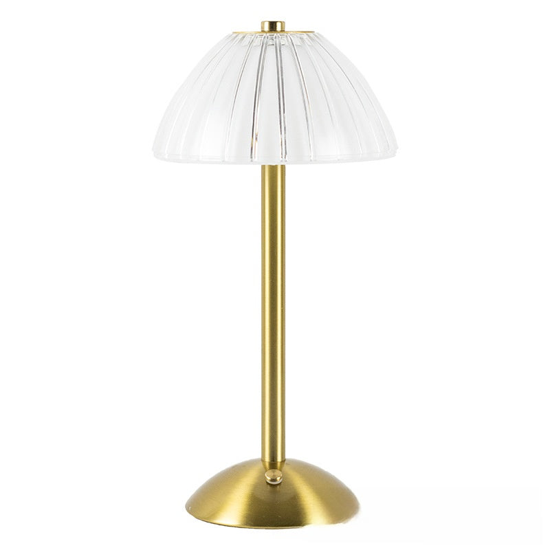 Table lamp with brass base and white pleated shade on a white background