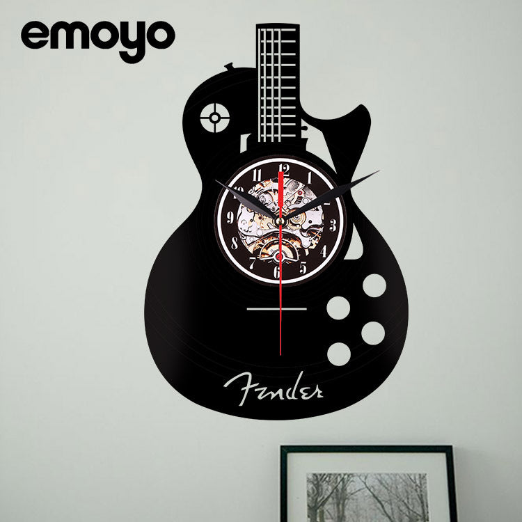 Guitar-shaped wall clock with Fender logo on a gray wall, featuring the brand 'emoyo'.