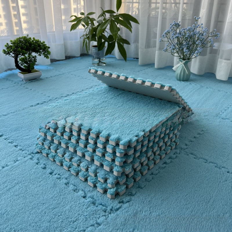Blue foam puzzle mat on a floor with plants and curtains in the background