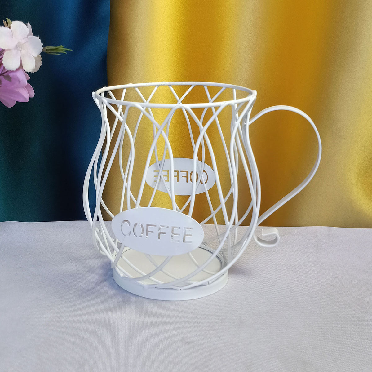 White wire  coffee capsules holder with 'COFFEE' label on a gray surface.