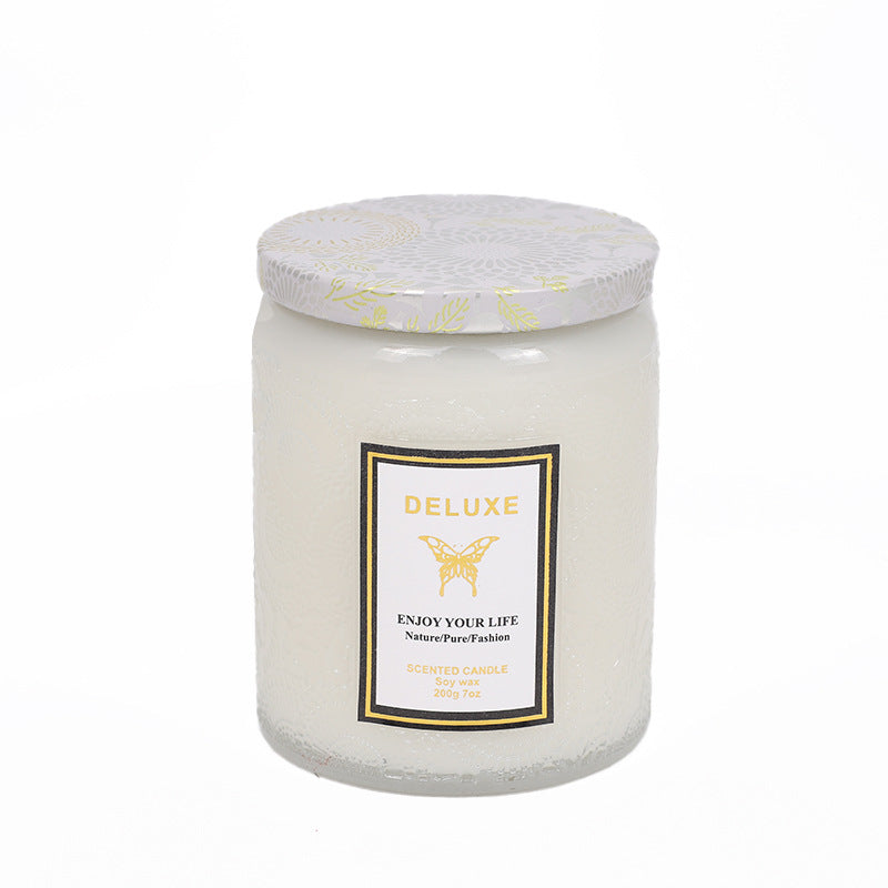 White candle in a glass jar with a decorative label on a white background