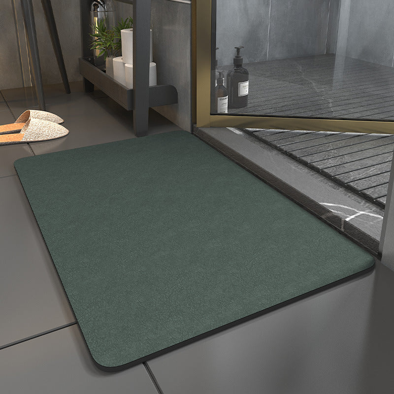 Green doormat in front of a glass door with a shower area in the background