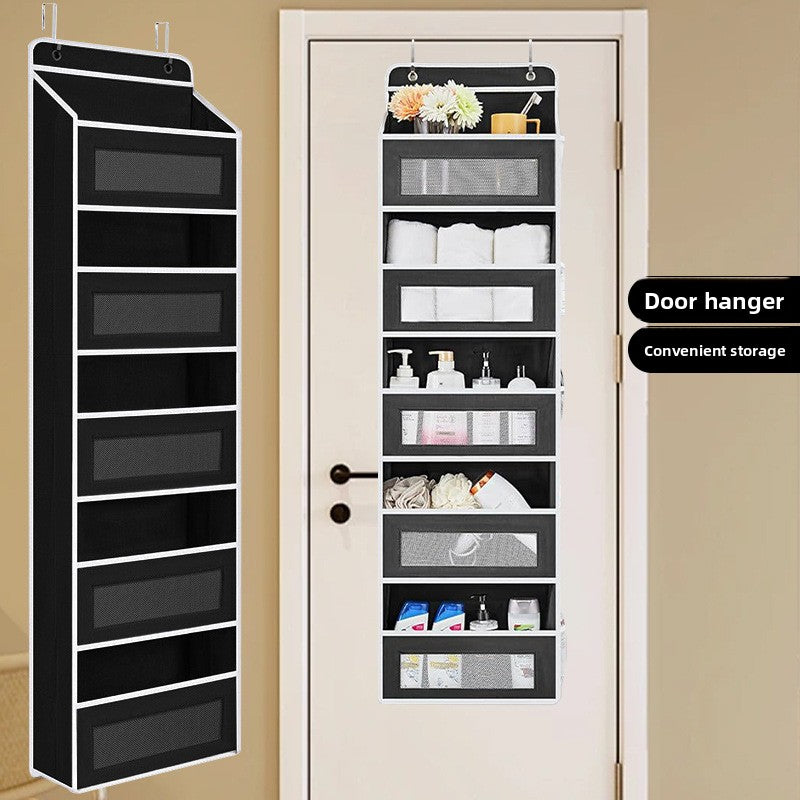 Black over-the-door shoe organizer with various items on a white door against a beige wall.