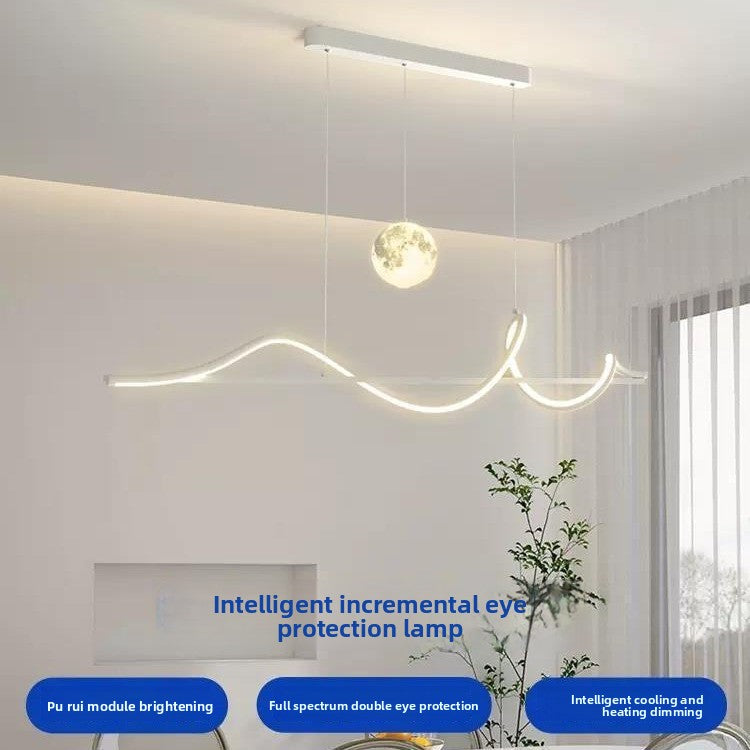 Modern ceiling light fixture in a room with a plant and window.