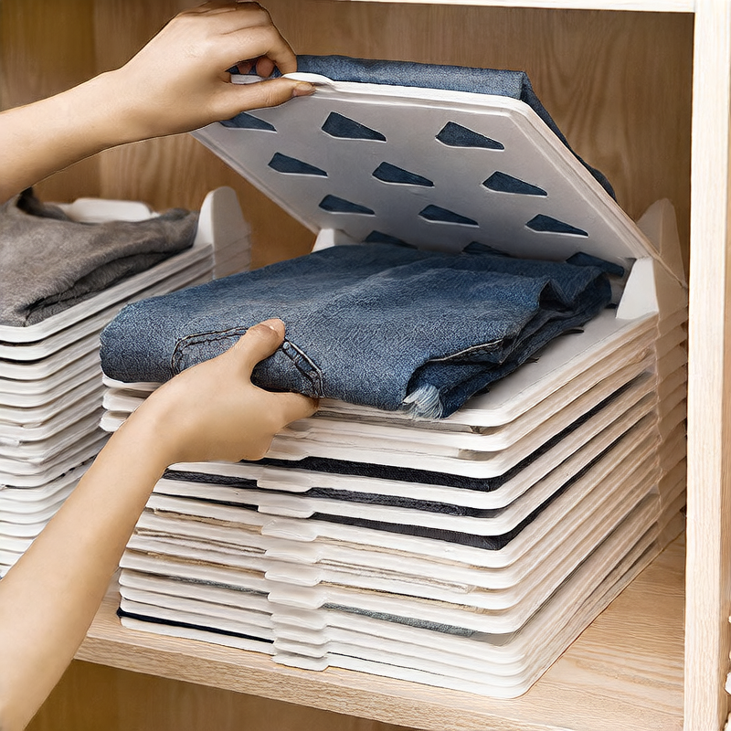 Person organizing folded jeans into a stack using a white storage box with a lid.