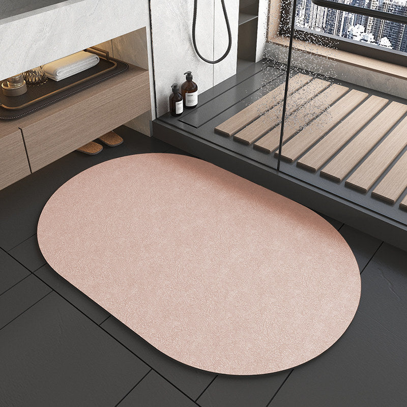 Beige oval rug on a dark tiled floor with a bathroom setting in the background.