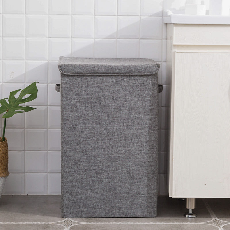 Gray laundry basket in a bathroom setting with white tiled walls and a cabinet.