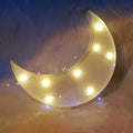 Crescent moon-shaped light with string lights on a fluffy surface