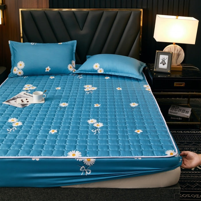 Blue floral mattress cover on a bed in a bedroom setting with a lamp and nightstand.