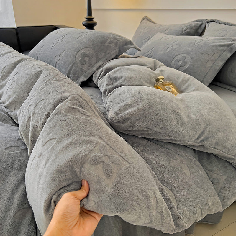 Gray textured comforter on a bed with a hand holding it, in a bedroom setting.
